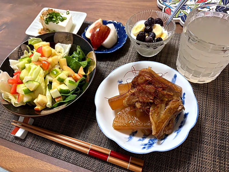 Braised pork and daikon on a blue and white plate, with a large chopped salad, cold tofu, fruit and yogurt
