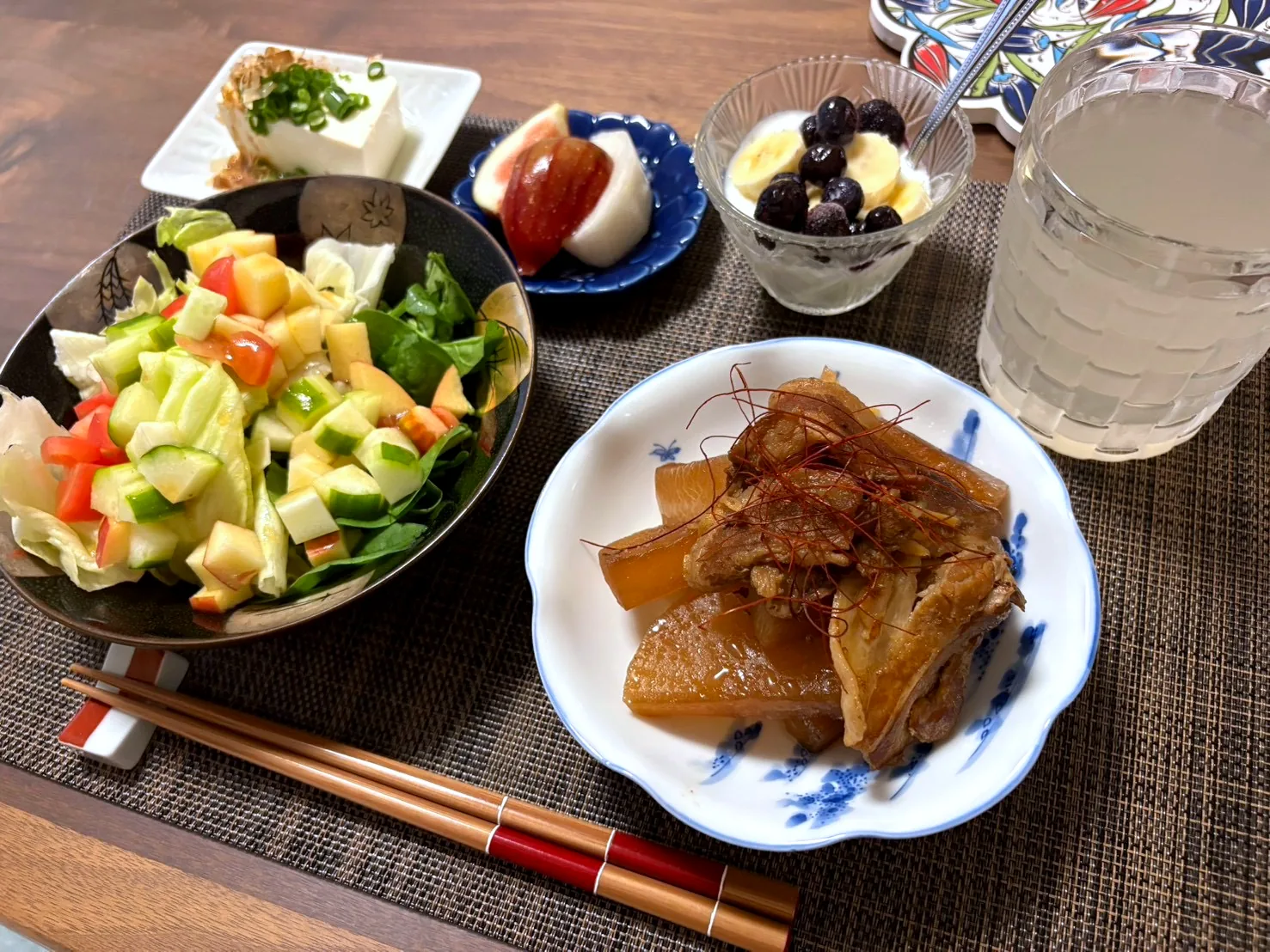 Braised pork and daikon on a blue and white plate, with a large chopped salad, cold tofu, fruit and yogurt