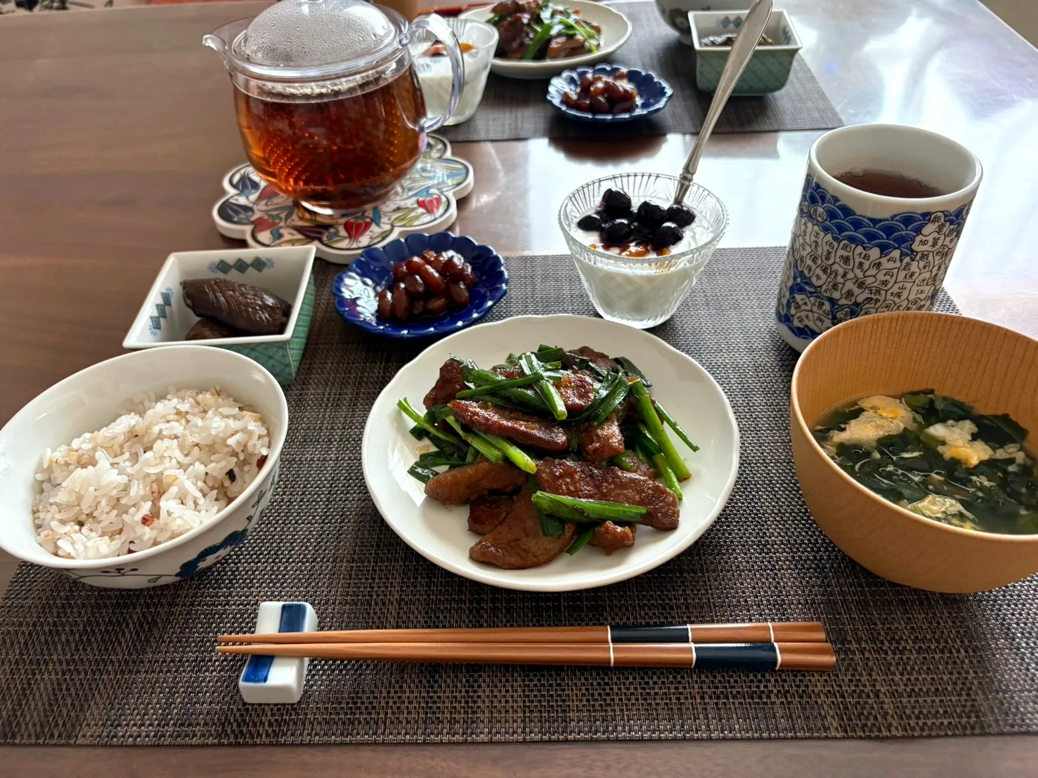 Japanese breakfast with stir-fried liver and garlic chives, a bowl of multigrain rice, egg and wakame soup, small side dishes and tea