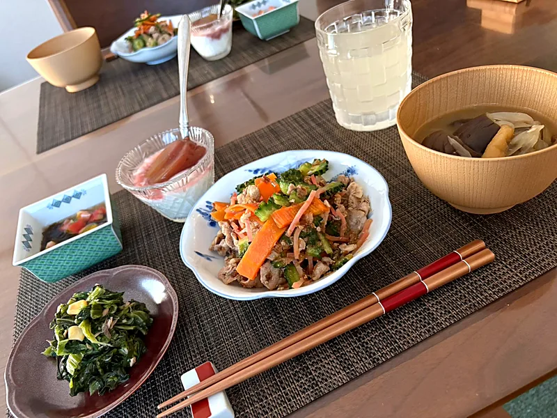 Japanese breakfast tray with a meat and vegetable stir-fry, a small dish of dark greens, soup in a wooden bowl and a cold drink